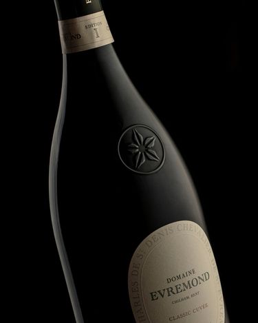 Close-up of a Domaine Evremond Classic Cuvée bottle showcasing premium craftsmanship. This English quality sparkling wine from Chilham, Kent is presented against a dark background emphasizing refinement. The label and embossed emblem highlight the traditional method of production synonymous with the estate.