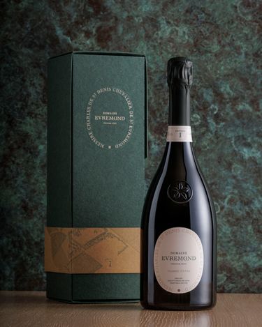 A bottle of Domaine Evremond Classic Cuvée English quality sparkling wine is displayed alongside its branded box. The elegant bottle features a clear label with gold and black text, emphasizing premium craftsmanship. The dark green box and refined packaging highlight the estate’s attention to detail in presenting its sparkling wine.