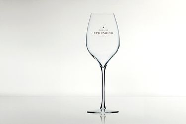 A clear, branded wine glass featuring the Domaine Evremond logo against a minimalist light background. The glass is slender and elegant, designed specifically for enjoying English quality sparkling wine, reflecting premium craftsmanship and refined presentation.