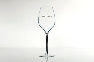 A clear, branded wine glass featuring the Domaine Evremond logo against a minimalist light background. The glass is slender and elegant, designed specifically for enjoying English quality sparkling wine, reflecting premium craftsmanship and refined presentation.